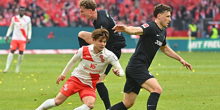 Mainz Mittelfeldspieler' Kaishu Sano im Duell mit Freiburgs Patrick Osterhage und Maximilian Eggestein